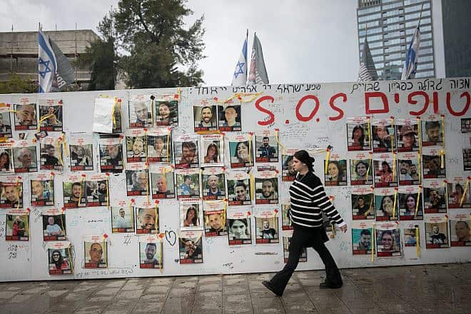 People walk by photographs of Israelis held hostage by Hamas terrorists, in Tel Aviv, March 19, 2024. Photo by Miriam Alster/Flash90.