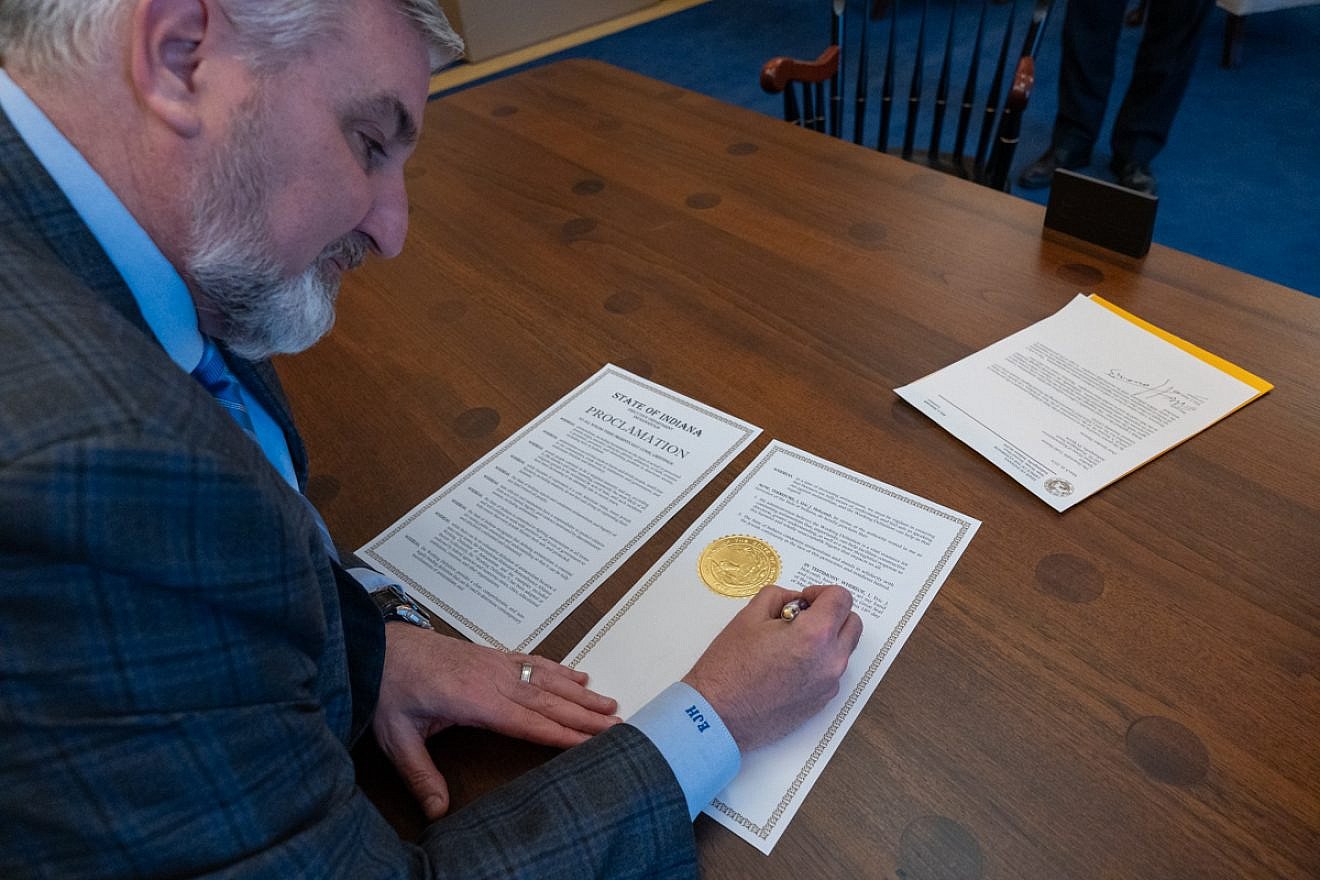 Indiana Gov. Eric Holcomb (R) signs a proclamation that states, in part, that his administration believes that the IHRA working definition of Jew-hatred "is a vital resource for combating antisemitism" on March 18, 2024. Credit: Courtesy of Indiana governor's office.