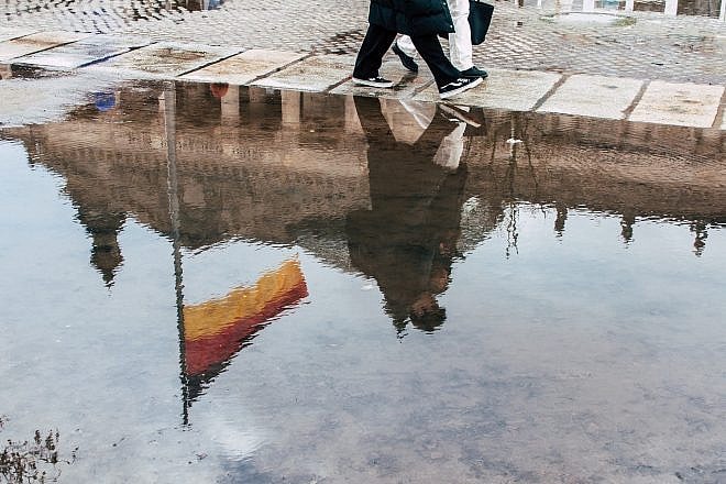 The flag of Germany reflected in a puddle. Credit: wal_172619/Shutterstock.
