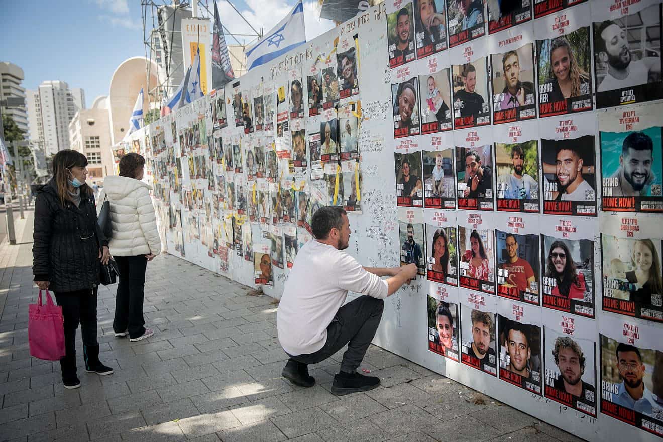 A man posts photographs of the Israelis still being held captive in the Gaza Strip by Hamas terrorists at "Hostages Square" in Tel Aviv on March 4, 2024. Photo by Miriam Alster/Flash90.