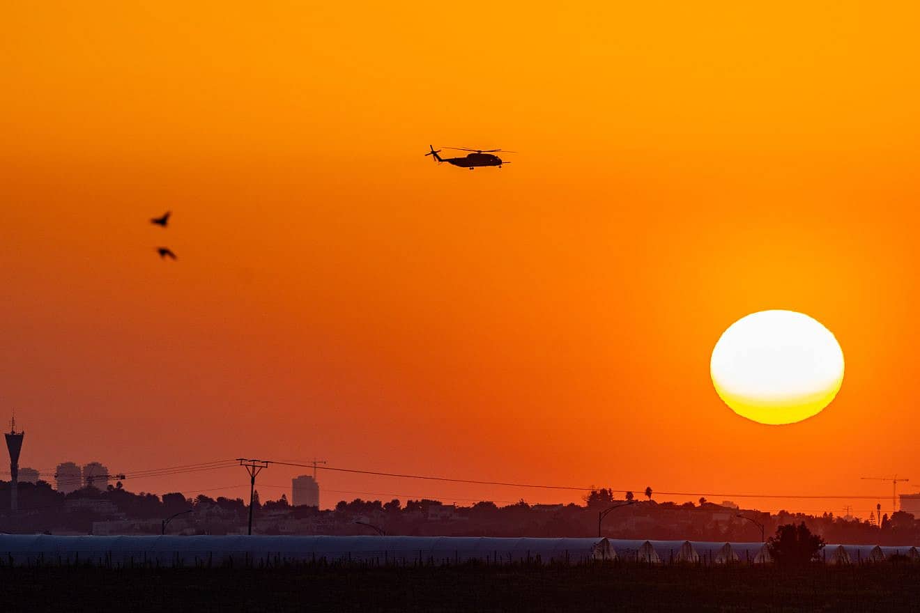 A military helicopter flies at sunset near the Israeli border with the Gaza Strip, March 11, 2024. Photo by Chaim Goldberg/Flash90.