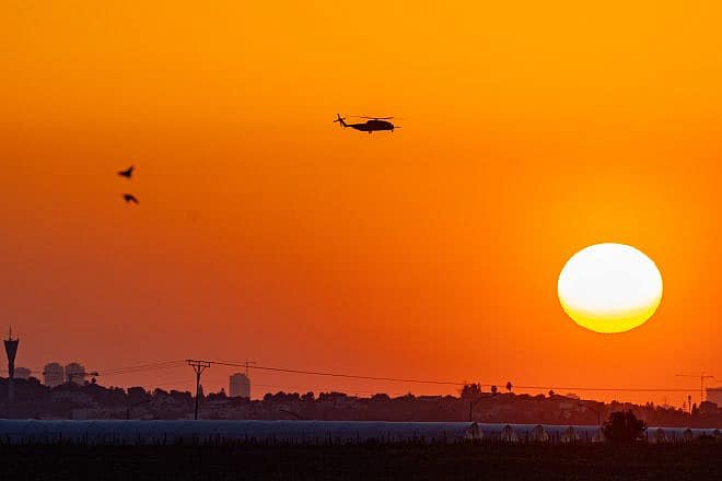 A military helicopter flies at sunset near the Israeli border with the Gaza Strip, March 11, 2024. Photo by Chaim Goldberg/Flash90.