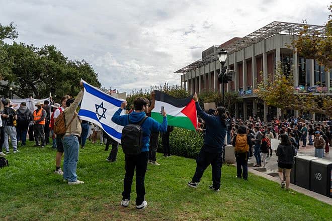 At a protest at UC Berkeley, two pro-Israel protesters hold up an Israeli flag while two pro-Palestinian protesters stand in front of it with a Palestinian flag, Oct. 25, 2023. Credit: Kefr4000 via Wikimedia Commons.