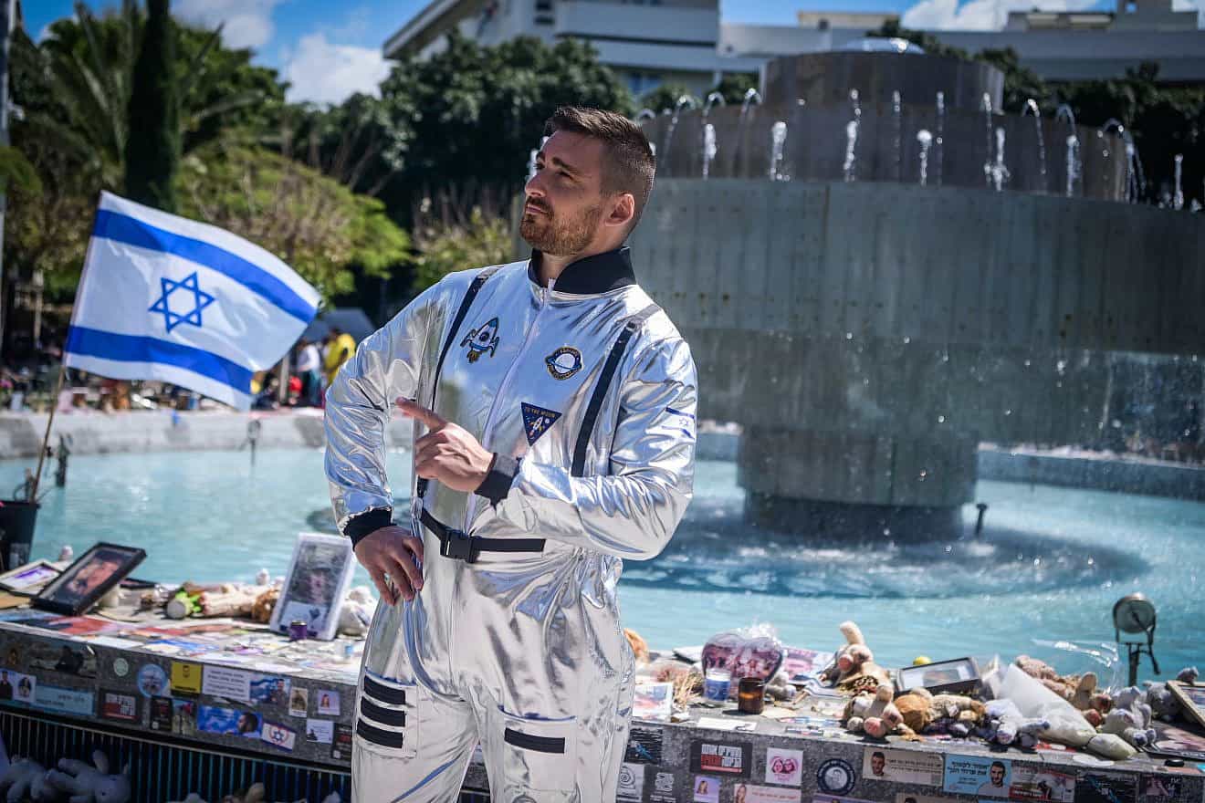 At Dizengoff Square in  Tel Aviv, a man dons a costume ahead of the Jewish holiday of Purim in the backdrop of photos of the hostages being held captive by Hamas in the Gaza Strip, March 22, 2024. Photo by Avshalom Sassoni/Flash90.