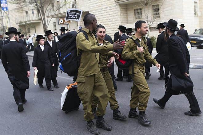 Israeli soldiers walk by a protest in Jerusalem attended by hundreds of thousands of ultra-Orthodox Jews against a proposal to introduce compulsory military service to the haredi community, March 02, 2014. Photo by Nati Shohat/Flash90.