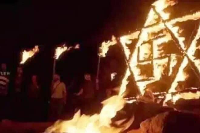 Palestinian rioters burn a Star of David with swastika in Samaria. Screenshot: Social media.