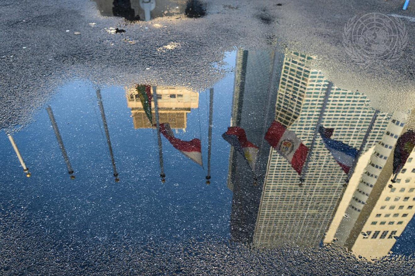 A reflection of flags being raised at U.N. headquarters in New York City. Credit: Manuel Elías/U.N. Photo.