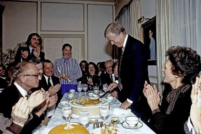 U.S. President Jimmy Carter cuts his birthday cake at party hosted by Esther Coopersmith (center in blue-striped shirt) at her home in Potomac, Md. Credit: Mark Reinstein/Shutterstock.