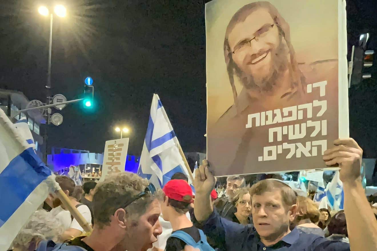 Hagay Lober holds a placard in Jerusalem depicting his son Staff Sgt. (res.) Elisha Yehonatan Lober, who was killed action in Gaza in December, and reading, "Enough of the demonstrations and the violent discourse, March 31, 2024. Source: Social media.