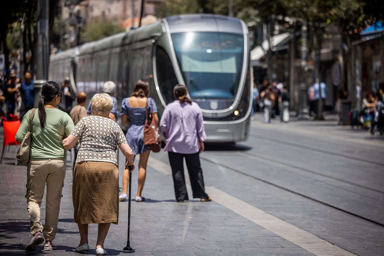 A caregiver assists an elderly woman on Jaffa Road in Jerusalem, July 2, 2023. Photo by Nati Shohat/Flash90.