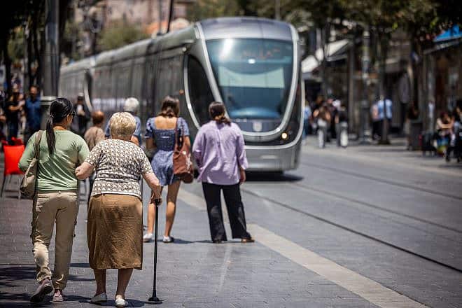 A caregiver assists an elderly woman on Jaffa Road in Jerusalem, July 2, 2023. Photo by Nati Shohat/Flash90.