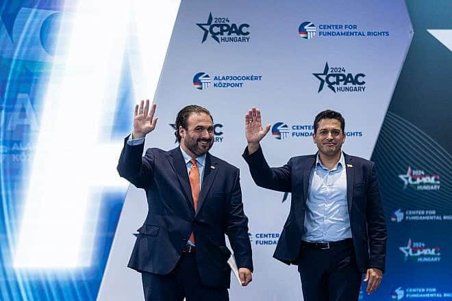 Israeli Minister for Diaspora Affairs and Combating Antisemitism Amichai Chikli (right) and Bryan Leib, a senior fellow at the Center for Fundamental Rights, wave to the crowd at CPAC Hungary on April 25, 2024. Credit: Courtesy of CPAC Hungary.
