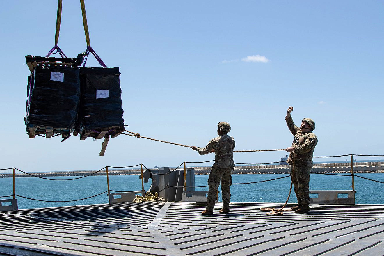 U.S. Army Soldiers assigned to the 7th Transportation Brigade (expeditionary) use a rope to stabilize humanitarian aid while it is lifted by a crane aboard the “MV Roy P. Benavidez” to support the Joint Logistics Over-the-shore (JLOTS) operation, in the Port of Ashdod, Israel, on May 13, 2024. Credit: Staff Sgt. Malcolm Cohens-Ashley/U.S. Army Photo.