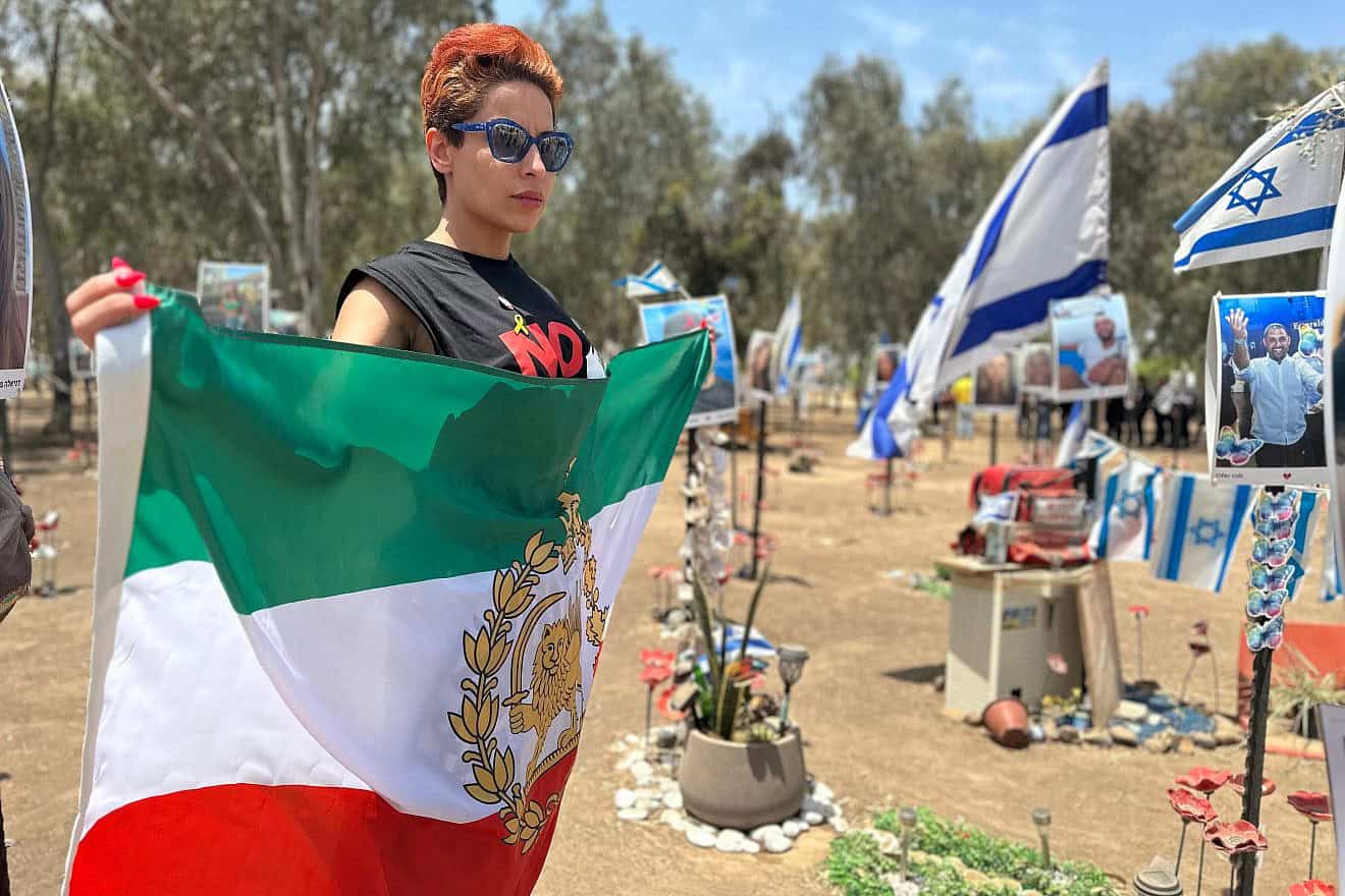 Iranian-British human rights activist Elaaheh Jamali holds a pre-Islamic Revolution Iranian flag at the site of the Supernova music festival massacre near Kibbutz Re'im, May 23, 2024. Credit: Courtesy of ELNET.