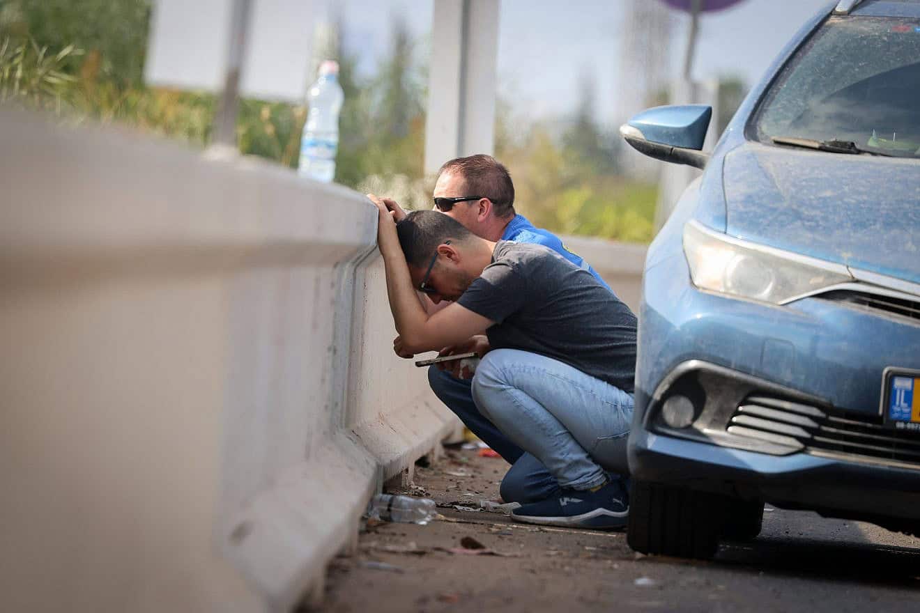 People take cover on a road near Tel Aviv as air-raid sirens warn of incoming rocket fire from the Gaza Strip, Oct. 10, 2023. Photo by Yossi Zamir/Flash90.