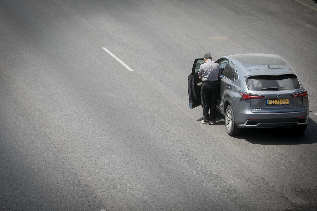 A man stands still as a two-minute siren sounded across Israel, marking Memorial Day, which commemorates the fallen Israeli soldiers and victims of terror, on the Ayalon Highway in Tel Aviv on May 13, 2024. Photo by Miriam Alster/Flash90.