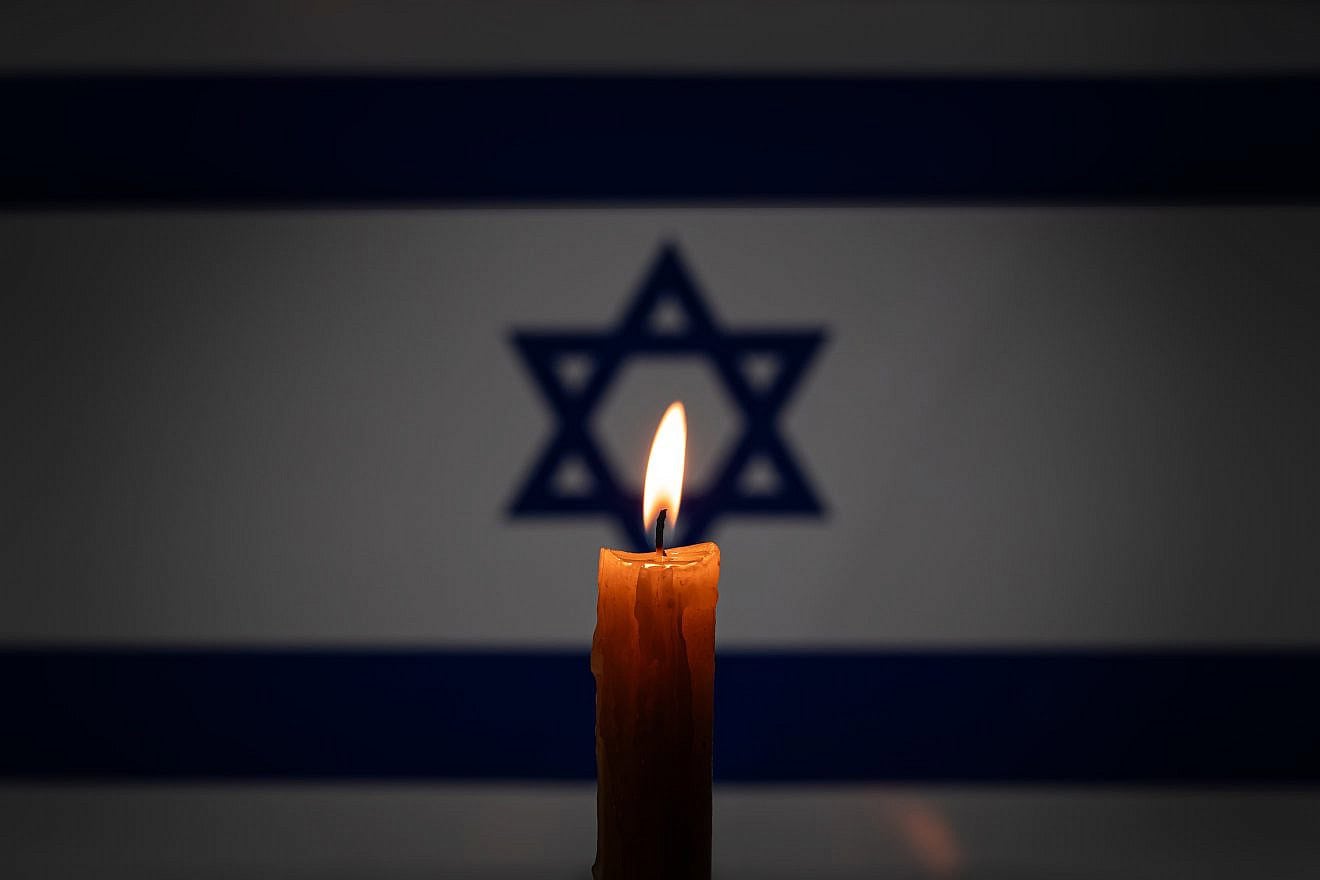 A burning candle on the background of the Israeli flag on Yom Hashoah, Holocaust Remembrance Day. Credit: Melnikov Dmitriy/Shutterstock.