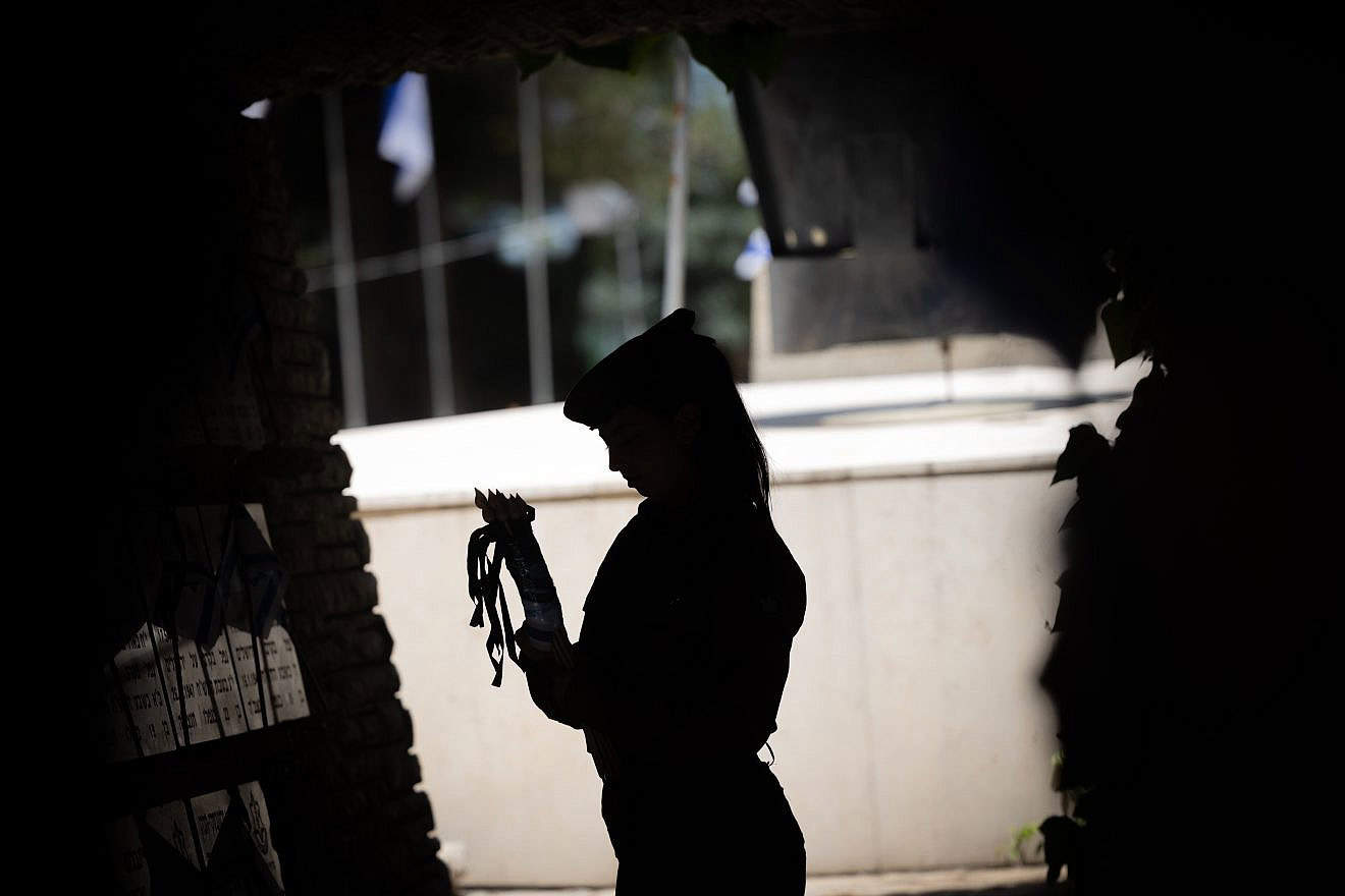 An Israeli soldier places flags around the Mount Herzl Military Cemetery in Jerusalem ahead of Yom Hazikaron, May 8, 2024. Photo by Yonatan Sindel/Flash90.