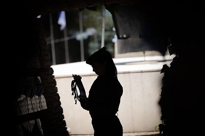 An Israeli soldier places flags around the Mount Herzl Military Cemetery in Jerusalem ahead of Yom Hazikaron, May 8, 2024. Photo by Yonatan Sindel/Flash90.