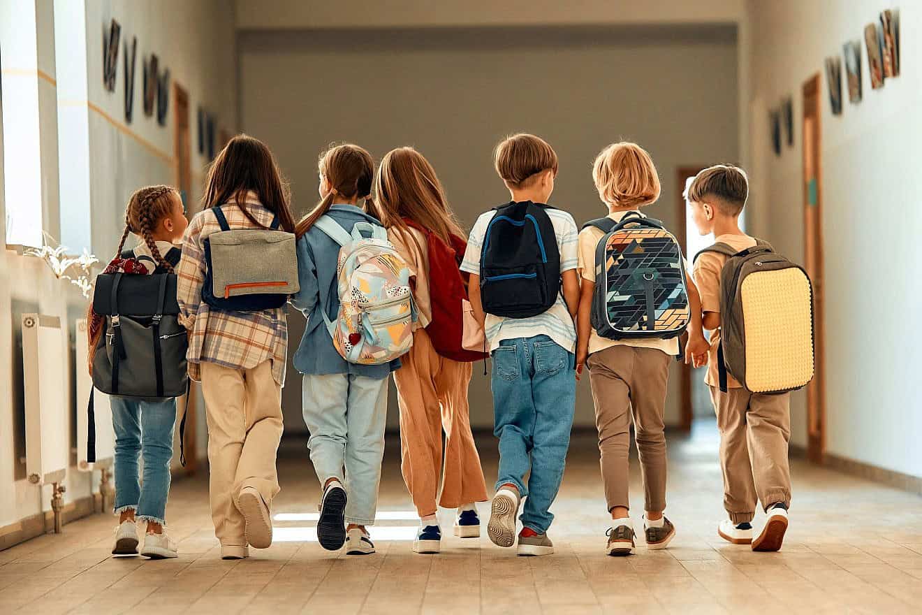 A group of children with backpacks walk along the school corridor. Credit: Orion Production/Shutterstock.