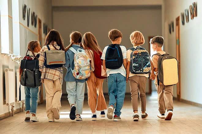 A group of children with backpacks walk along the school corridor. Credit: Orion Production/Shutterstock.