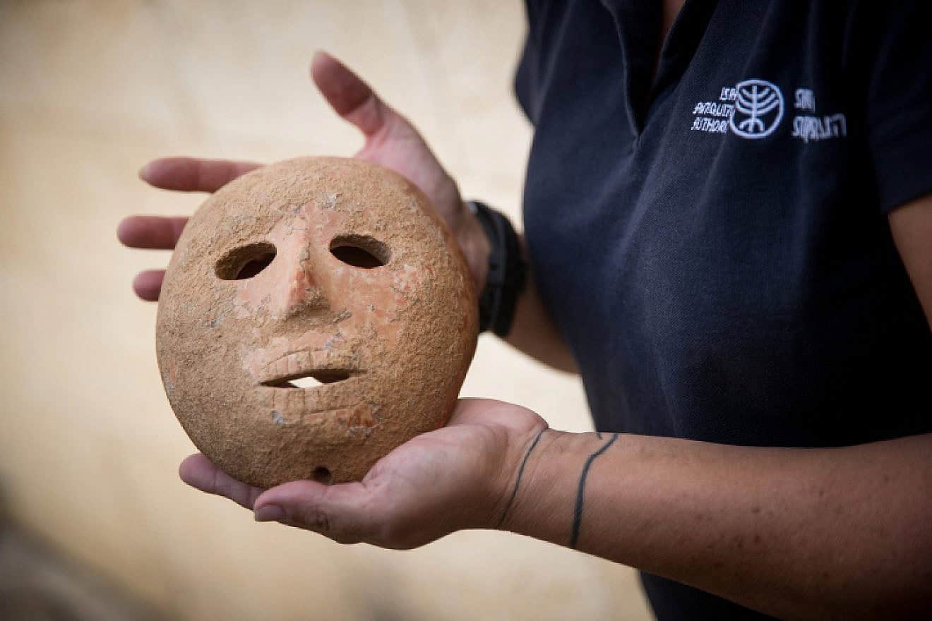 Ronit Lupo of the Israel Antiquities Authority holds a 9,000-year-old stone mask recovered from thieves by the Antiquities Authority Theft Prevention Unit in southern Hebron Hills, during a press conference in Jerusalem on Nov. 28, 2018. Photo by Yonatan Sindel/Flash90.