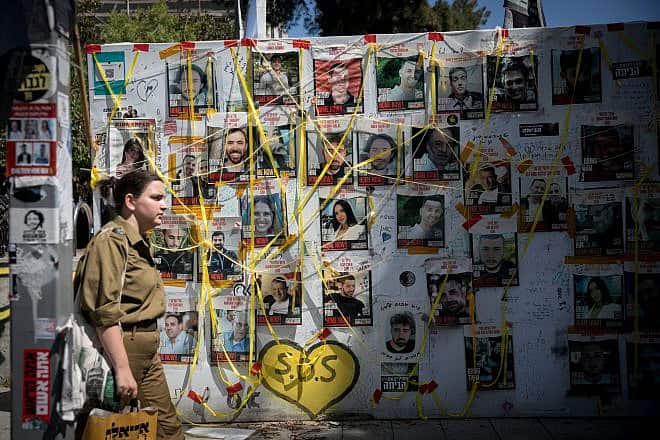 A woman walks past pictures  at "Hostage Square" in Tel Aviv of Israelis held hostage by Hamas terrorists in Gaza, June 16, 2024. Photo by Miriam Alster/Flash90.