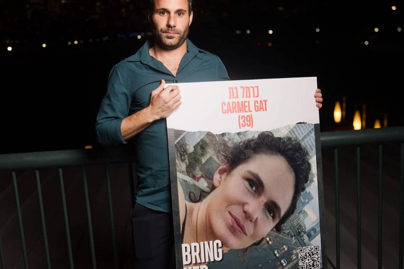 Or Gat, who survived the Oct. 7 terror attacks, holds up a picture of his sister, Carmel Gat, who is being held hostage by Hamas. Credit: Courtesy of Jewish National Fund-USA.