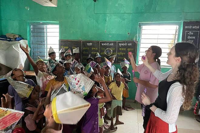OU relief mission members Ariela Guakil (left) and Shayna Sklar play with schoolchildren in the Mokhada village. Credit: Courtesy.