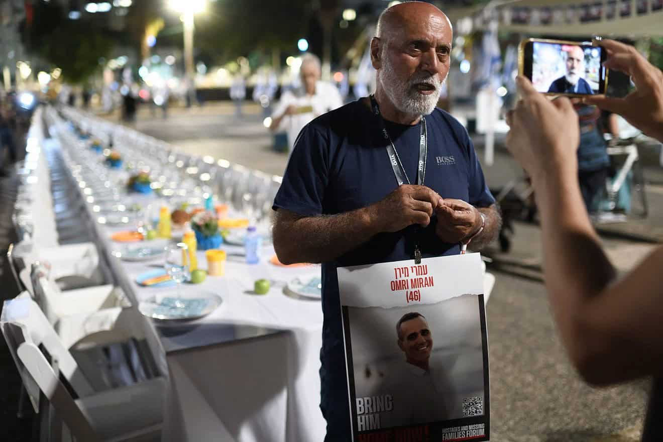 David Miran, the father of Omri Miran, who has been held hostage by Hamas terrorists in the Gaza Strip since the attacks in southern Israel on Oct. 7,  stands near a Shabbat table with more than 200 empty seats for the hostages, at the “Hostages Square,” outside of the Tel Avi Museum of Art, on Oct. 20, 2023. Photo by Gili Yaari /Flash90.