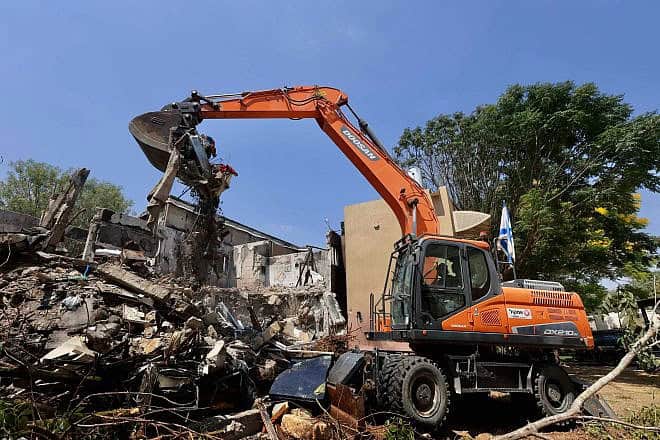 A bulldozer destroys a house that was damaged during the Oct. 7 massacre in Kibbutz Be'eri near the Israeli border with the Gaza Strip, as part of a project rebuilding the destroyed homes and infrastructure in the kibbutz, July 7, 2024. Photo by Oren Cohen/Flash90.