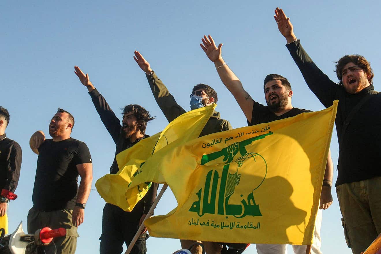 Supporters of the Lebanese Shi'ite movement Hezbollah perform a salute as they stand behind motorcycles carrying the group's flags in the southern Lebanese district of Marjayoun on the border with Israel on May 25, 2020. Photo by Mahmoud Zayyat/AFP via Getty Images.