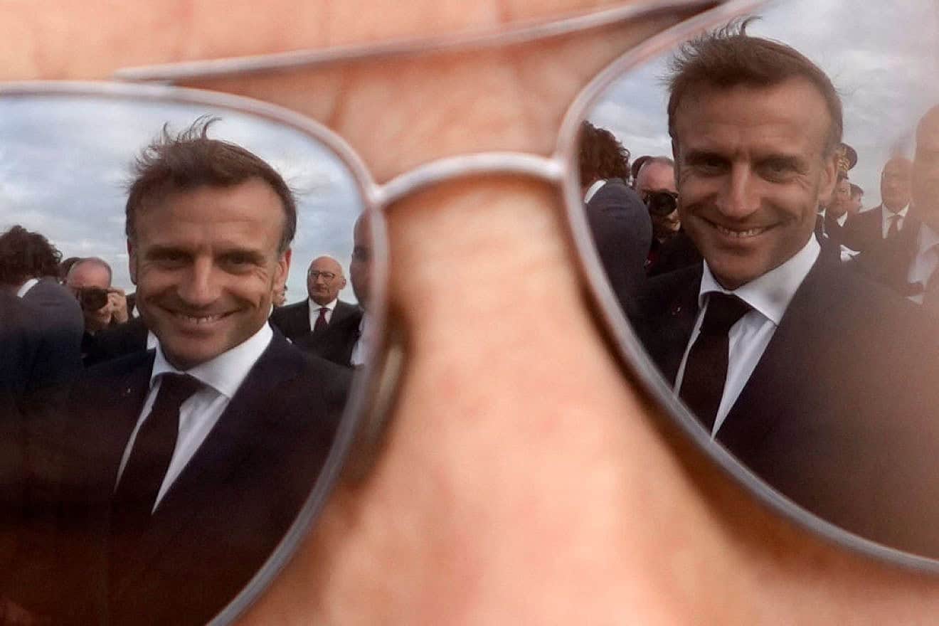French President Emmanuel Macron is reflected in the sunglasses of a resident as they converse following a ceremony at the Croix du Souvenir monument in Brittany on June 18, 2024. Credit: Christophe Ena/POOL/AFP via Getty Images.