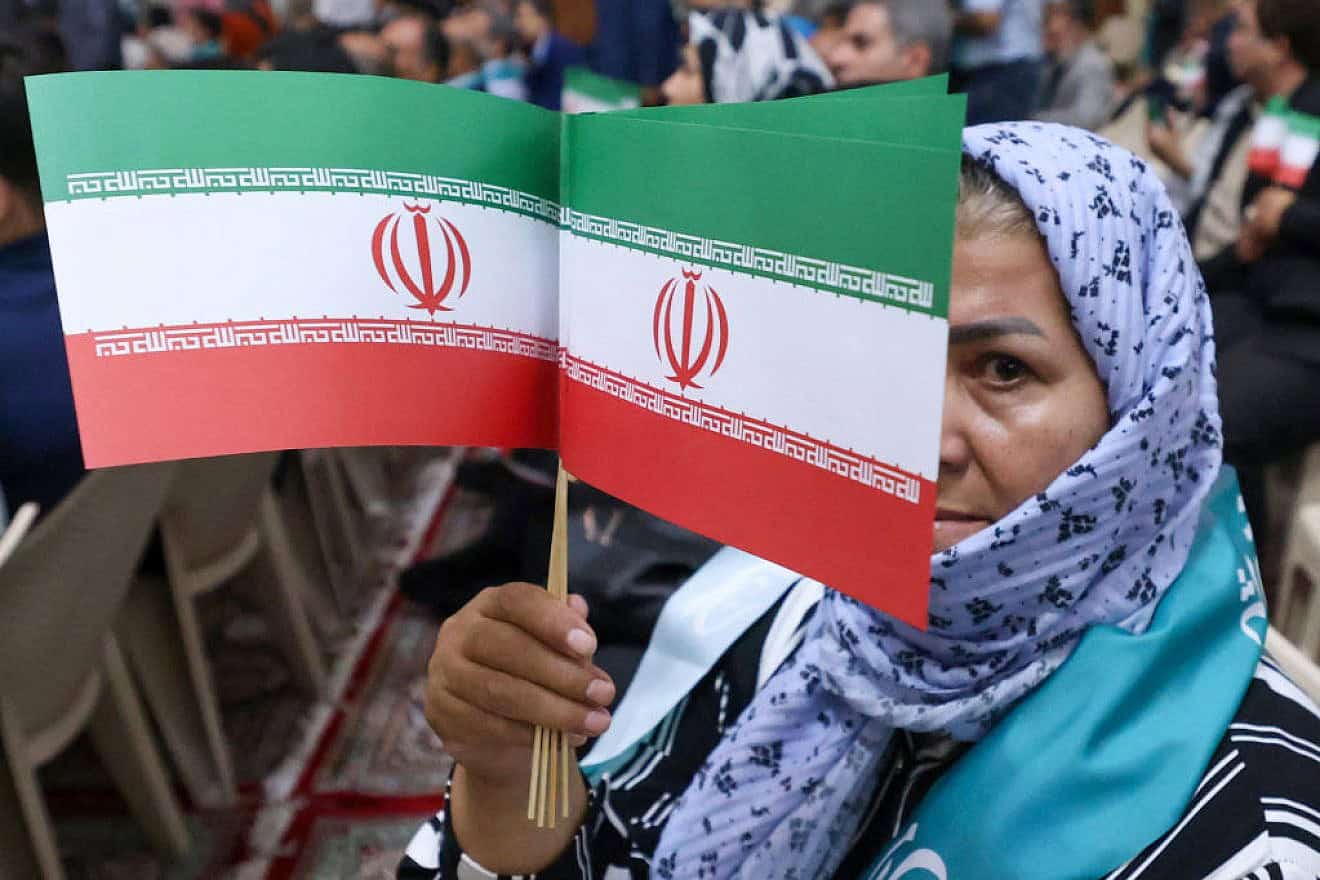 A woman waves Iranian flags as newly-elected president Masoud Pezeshkian visits the shrine of the Islamic Republic's founder Ayatollah Ruhollah Khomeini in Tehran on July 6, 2024. Photo by Atta Kenare/AFP via Getty Images.