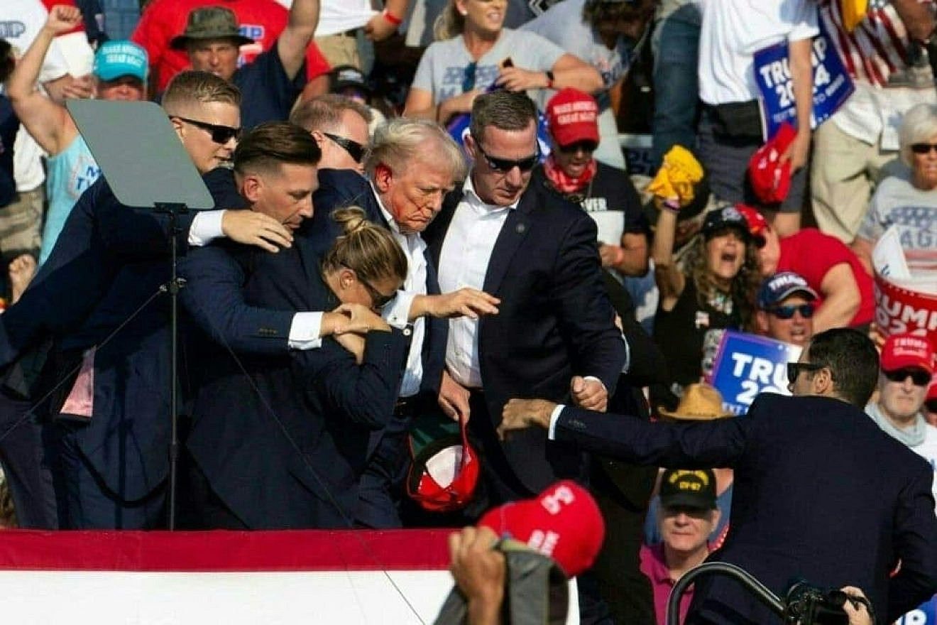 Republican presidential candidate Donald Trump is seen with blood on his face surrounded by secret service agents following an assassination attempt in Butler, Pennsylvania on July 13, 2024. Credit: Rebecca Droke / AFP via Getty Images.