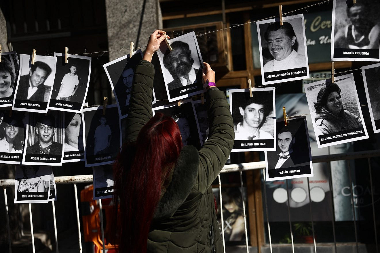 A woman hangs pictures of victims during a ceremony to commemorate the anniversary the Mutual Israelite Association of Argentina (AMIA) bombing attack in Buenos Aires on July 18, 2024. on the 30th anniversary of the 1994 bombing that left 85 dead and more than 300 wounded. Photo by Tomas Cuesta/AFP via Getty Images.