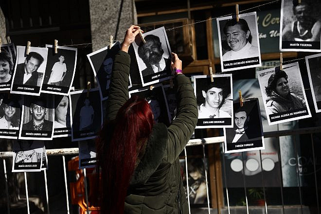 A woman hangs pictures of victims during a ceremony to commemorate the anniversary the Mutual Israelite Association of Argentina (AMIA) bombing attack in Buenos Aires on July 18, 2024. on the 30th anniversary of the 1994 bombing that left 85 dead and more than 300 wounded. Photo by Tomas Cuesta/AFP via Getty Images.
