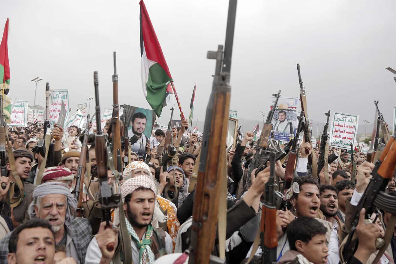 Yemenis brandish rifles, as well as flags of Yemen, Palestinian and Houthi emblems, and chant slogans during a demonstration staged against the latest aerial attacks hit Yemen's port city of Hodeidah, on July 26, 2024. Photo by Mohammed Hamoud/Getty Images.