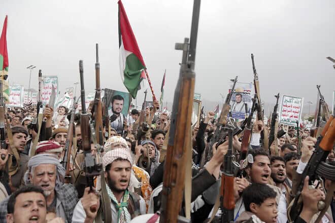 Yemenis brandish rifles, as well as flags of Yemen, Palestinian and Houthi emblems, and chant slogans during a demonstration staged against the latest aerial attacks hit Yemen's port city of Hodeidah, on July 26, 2024. Photo by Mohammed Hamoud/Getty Images.