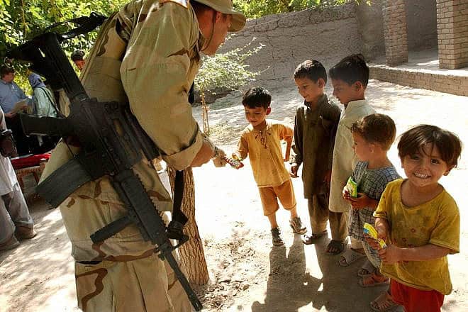 A U.S soldier gives candy and cake to children on the outskirts of Jalalabad city in the Nangarhar province east of Kabul, Oct. 3, 2005. Credit: Musadeq Sadeq/AFP via Getty Images.