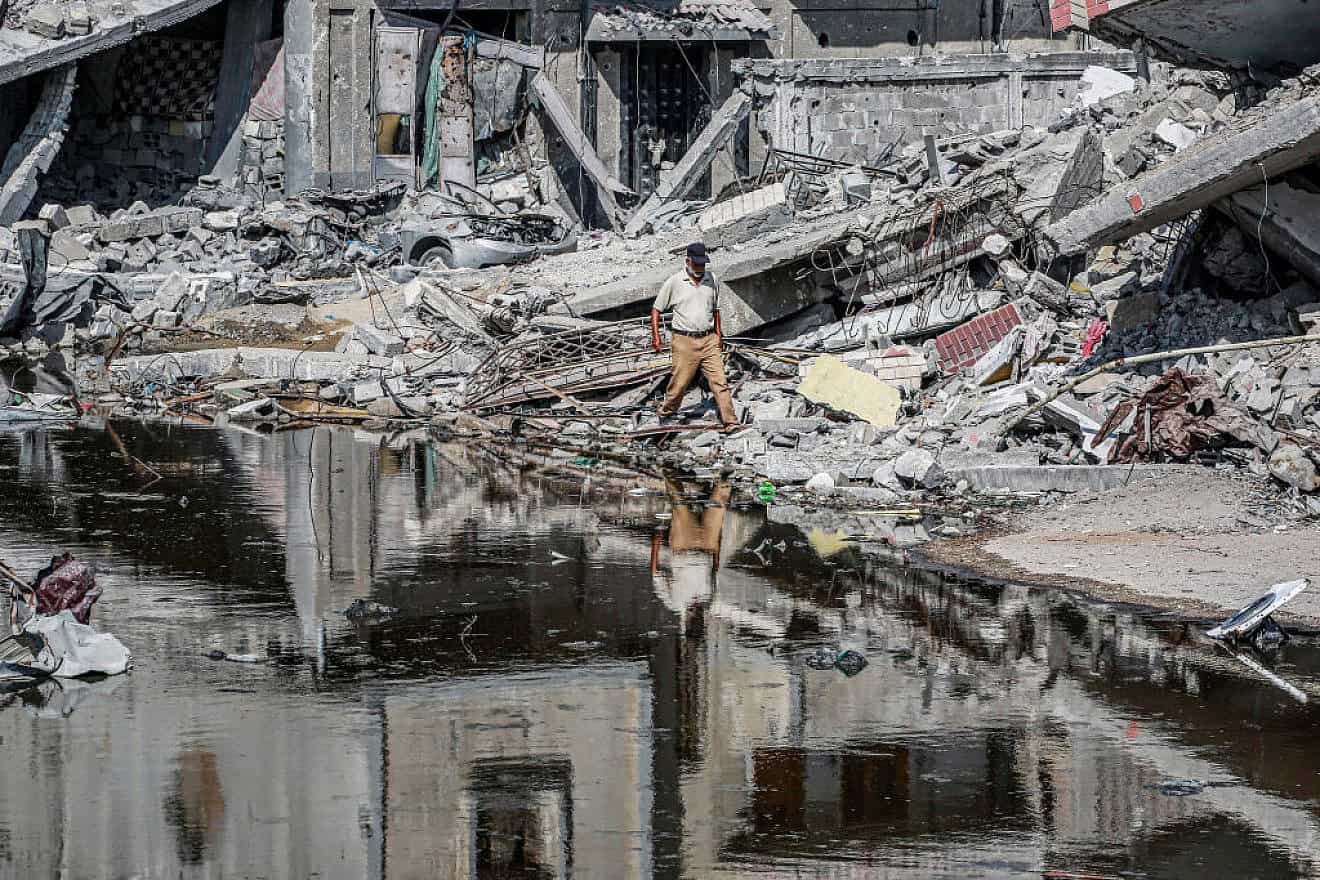 A man walks past destroyed buildings and sewage water erupting from collapsed underground pipes in Khan Younis, the southern Gaza Strip, July 8, 2024. Photo by Bashar Taleb/AFP via Getty Images.