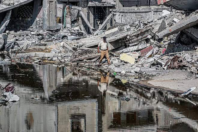A man walks past destroyed buildings and sewage water erupting from collapsed underground pipes in Khan Younis, the southern Gaza Strip, July 8, 2024. Photo by Bashar Taleb/AFP via Getty Images.
