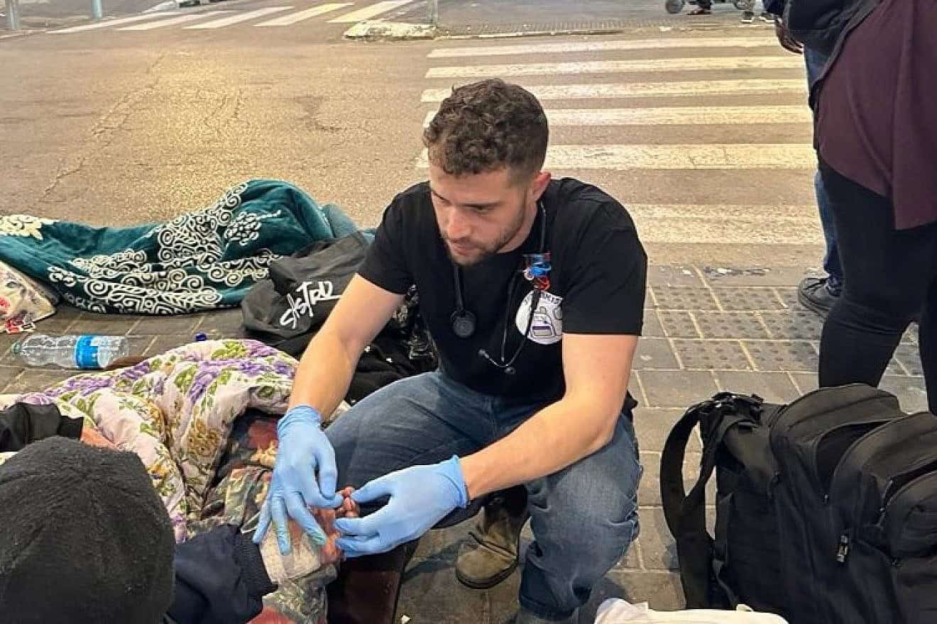 A medical student checks the circulation in a man's fingers. Credit: Courtesy of Street Medicine Tel Aviv.