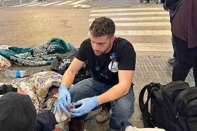 A medical student checks the circulation in a man's fingers. Credit: Courtesy of Street Medicine Tel Aviv.
