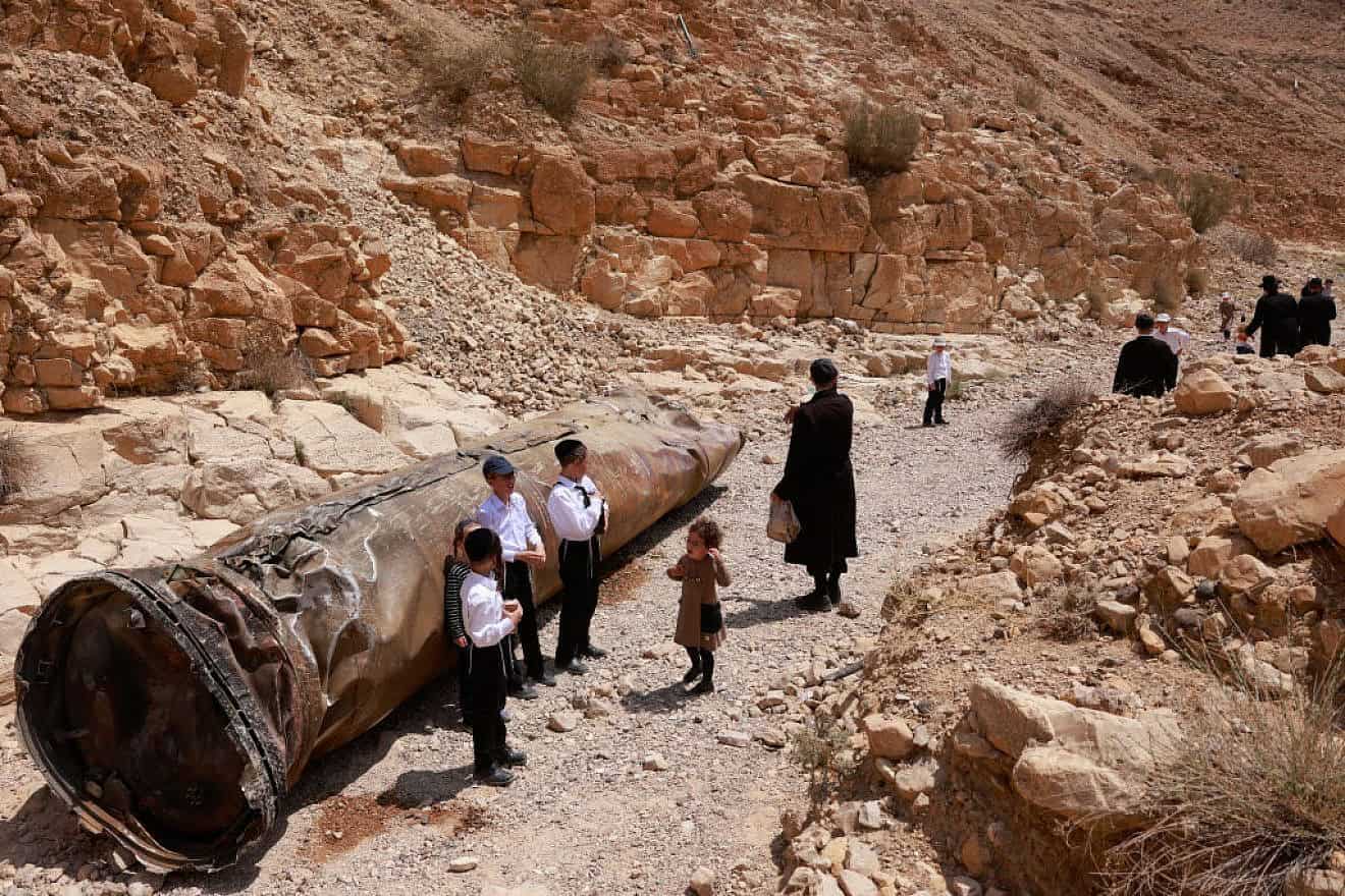 Jews near the Negev city of Arad gather around the remains of one of Iranian ballistic missiles Israel intercepted two weeks earlier, April 30, 2024. Photo by Menahem Kahana/AFP via Getty Images.