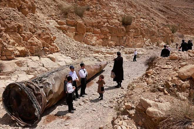 Jews near the Negev city of Arad gather around the remains of one of Iranian ballistic missiles Israel intercepted two weeks earlier, April 30, 2024. Photo by Menahem Kahana/AFP via Getty Images.