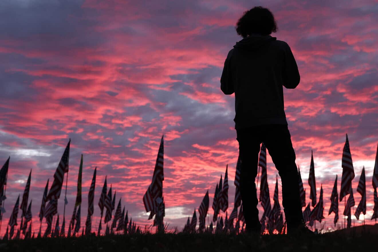 A person stands near the nearly 3,000 American flags honoring lives lost during the 9/11 terrorist attacks as the sun sets at Pepperdine University in Malibu, Calif., on Sept. 11, 2023. Photo by Mario Tama/Getty Images.