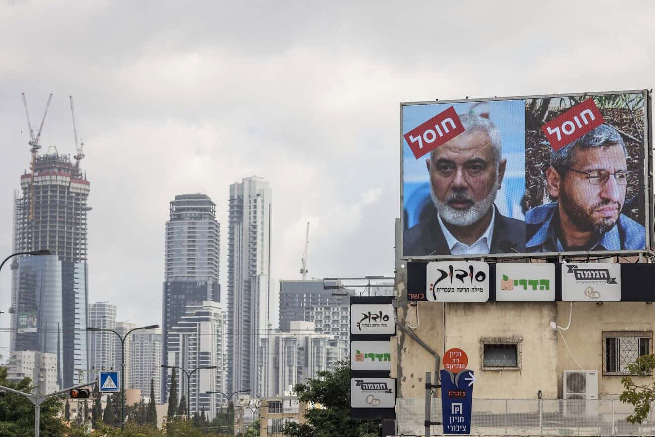 A billboard in Tel Aviv displays portraits of Hamas leaders Ismail Haniyeh (left), killed in Iran on July 31, and Mohammed Deif, killed last month in the Gaza Strip, with the word “assassinated” in Hebrew, Aug. 2, 2024. Photo by Oren Ziv/AFP via Getty Images.