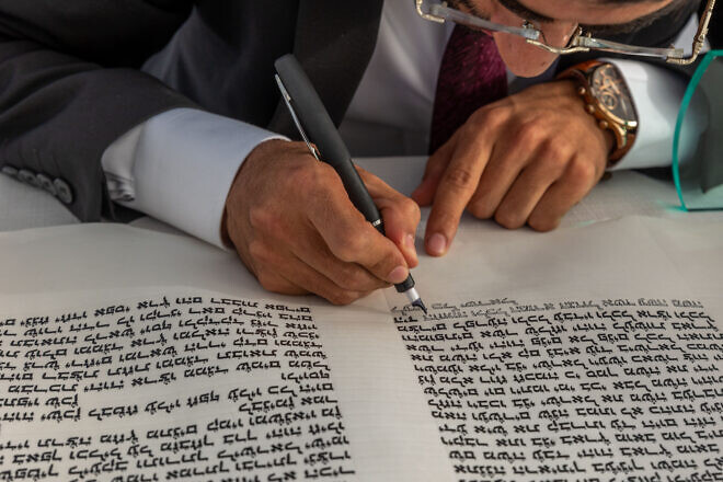A man fills in letters in a Torah scroll in Moshav Yashresh, Aug. 25, 2022. Photo by Yossi Aloni/Flash90.