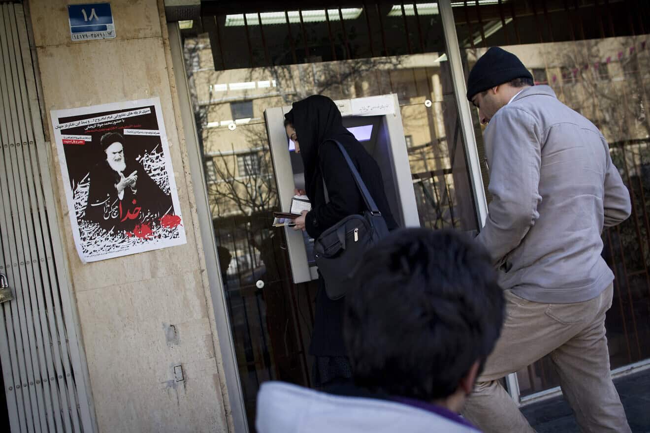 Iranians line up at an ATM as a portrait of the late founder of the Islamic Republic, Ayatollah Ruhollah Khomeini, is plastered on a bank branch in central Tehran, Feb. 26, 2012. Photo by Behrouz Mehri/AFP via Getty Images.
